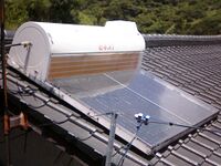 Calentador solar plano con tanque acumulador en una vivienda.