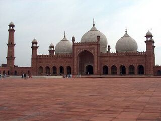 La [[Badshahi Masjid en Lahore, Pakistán con un iwan en el centro, tres cúpulas y cinco minaretes visibles.]]