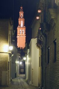 Imagen nocturna de la calle Mármoles de Écija con la torre de la Iglesia de San Gil al fondo. A la derecha se encuentra el Palacio de Almenara Alta[1].
